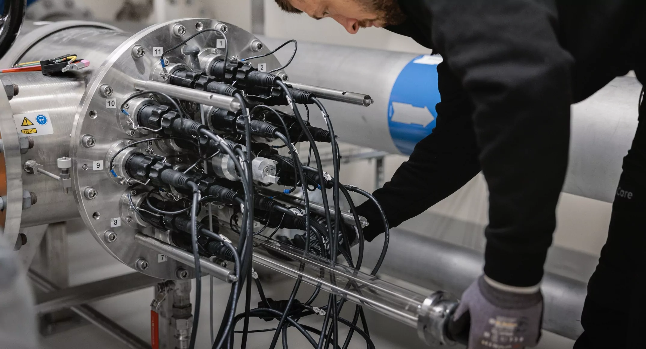Servicetekniker från Aqua & Care utför underhåll av UV-lampor och elkablar på en avancerad UV-anläggning för vattenrening.