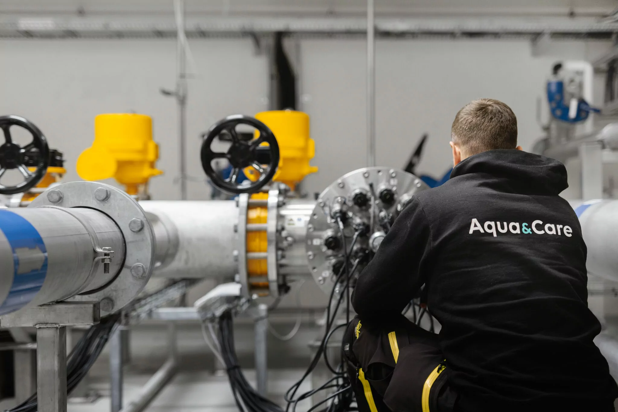 Servicetekniker från Aqua & Care arbetar på en UV-anläggning för vattenrening – professionell service i driftmiljö.